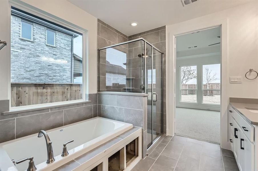 Bathroom featuring plus walk in shower, vanity, and tile patterned floors