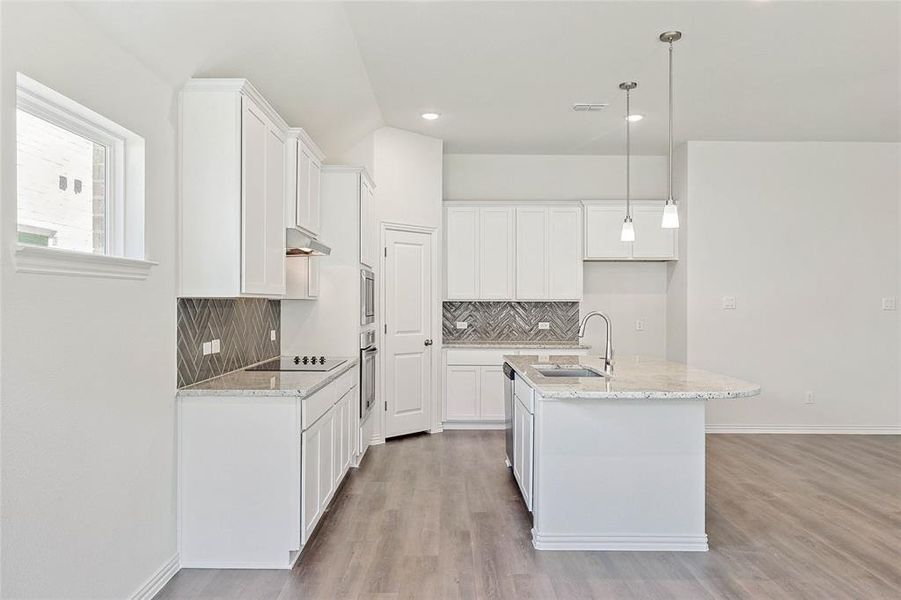 Kitchen featuring sink, light hardwood / wood-style flooring, white cabinets, and tasteful backsplash