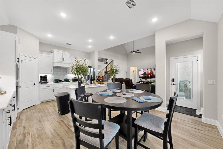 Dining area featuring light wood-style flooring, stairs, ceiling fan, lofted ceiling, and recessed lighting Dining area featuring light wood-style flooring, stairs, ceiling fan, lofted ceiling, and recessed lighting