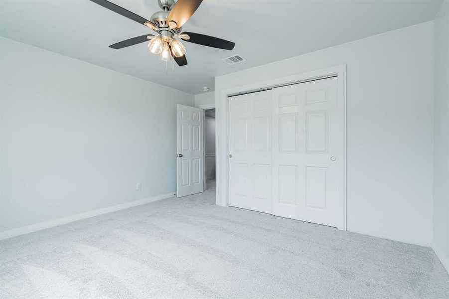 Unfurnished bedroom featuring light colored carpet, ceiling fan, and a closet