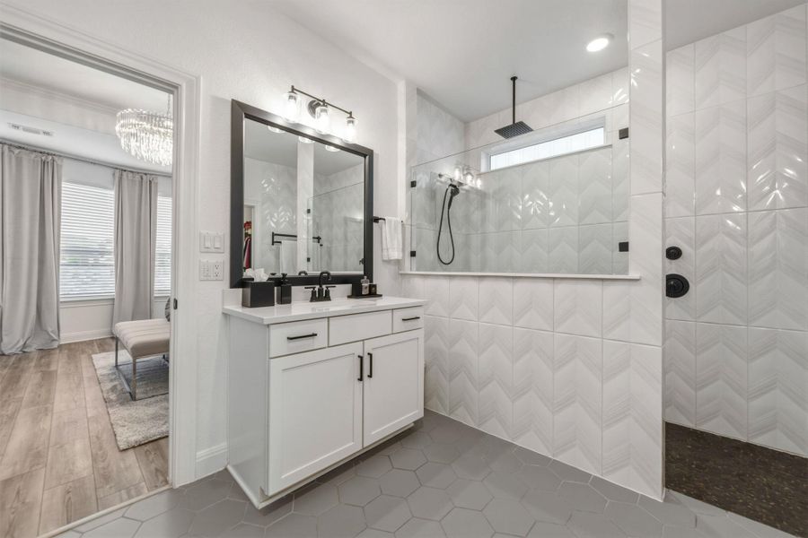 Bathroom featuring a dual vanity with white cabinetry and dark hardware, a rectangular framed mirror, and a three-light fixture