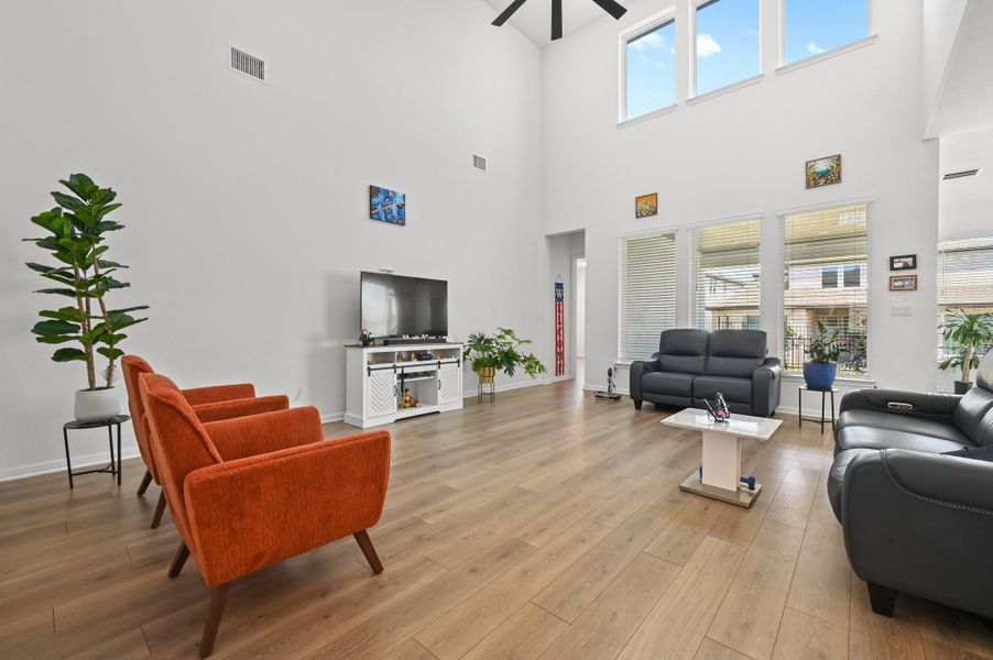 Double-height ceilings and tall windows illuminate the spacious main level with rich wood floors.