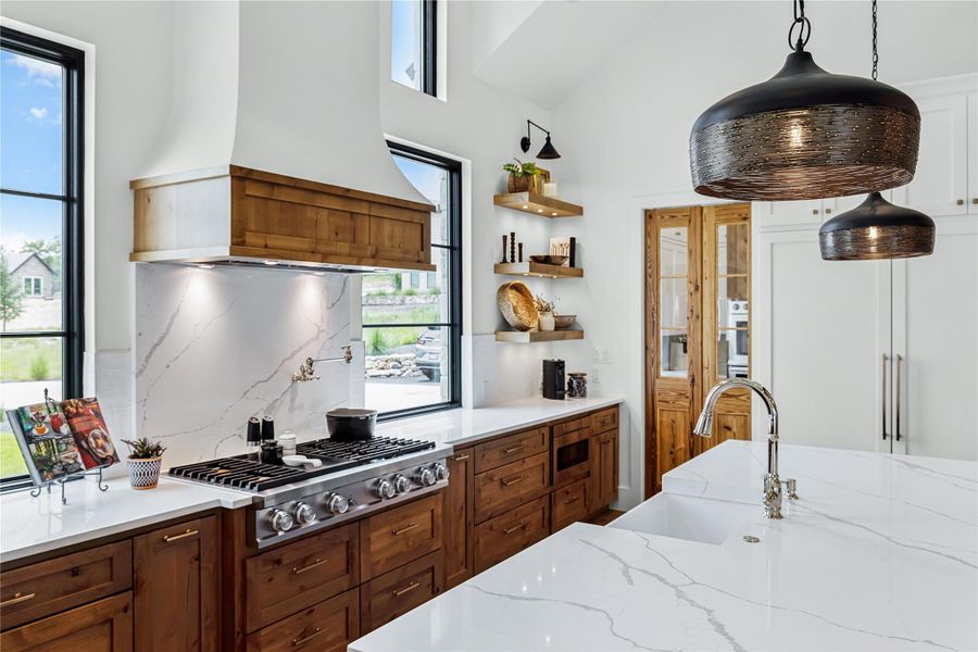 Kitchen featuring sink, premium range hood, hanging light fixtures, plenty of natural light, and stainless steel appliances