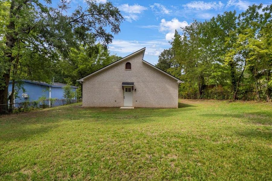 Back of property featuring a yard and brick siding