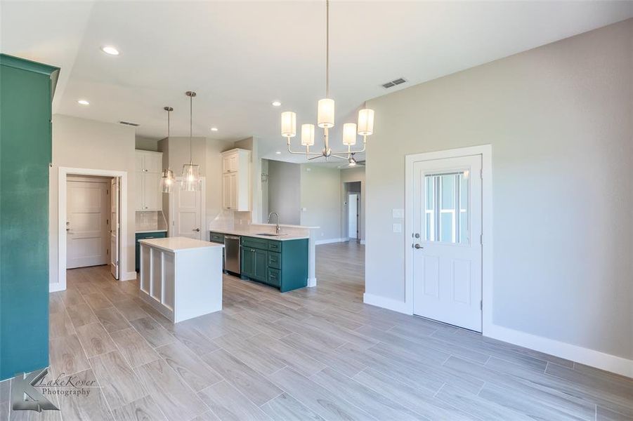 Kitchen with light countertops, a chandelier, recessed lighting, a peninsula, and a center island