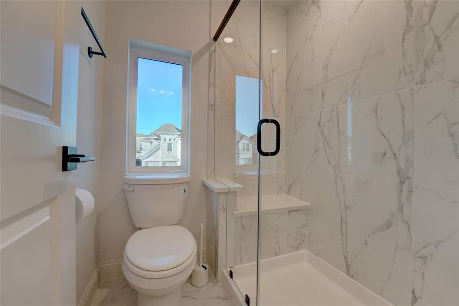 Bathroom with marble finish floor, baseboards, toilet, and a marble finish shower