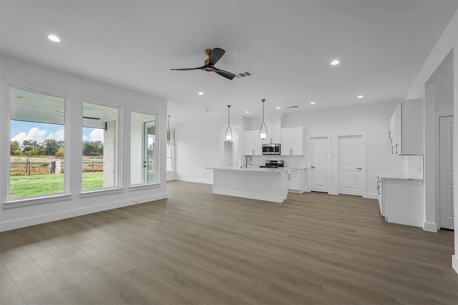 Unfurnished living room featuring wood finished floors, a ceiling fan, and recessed lighting Unfurnished living room featuring wood finished floors, a ceiling fan, and recessed lighting