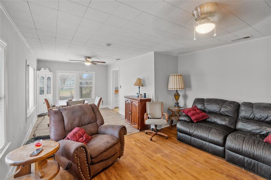 Living room with light hardwood / wood-style flooring, ornamental molding, and ceiling fan