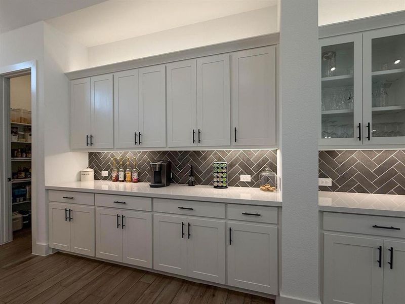 Built-ins with decorative backsplash, light stone countertops, and white cabinets Built-ins with decorative backsplash, light stone countertops, and white cabinets