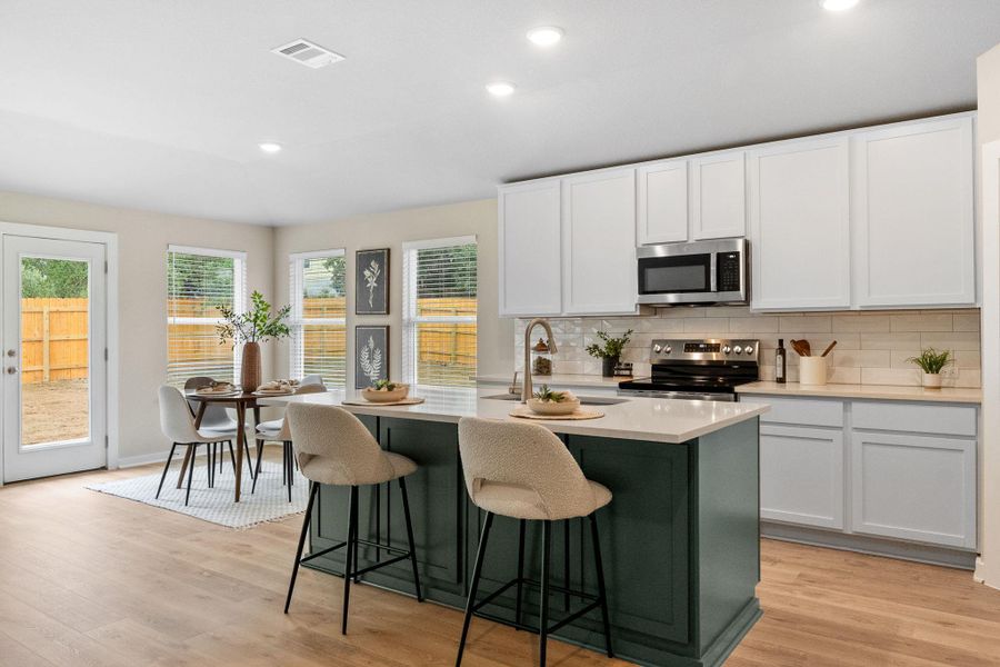 Kitchen with white cabinets, tasteful backsplash, green-grey contrasting island cabinets, stainless steel appliances, and recessed lighting Kitchen with white cabinets, tasteful backsplash, green-grey contrasting island cabinets, stainless steel appliances, and recessed lighting