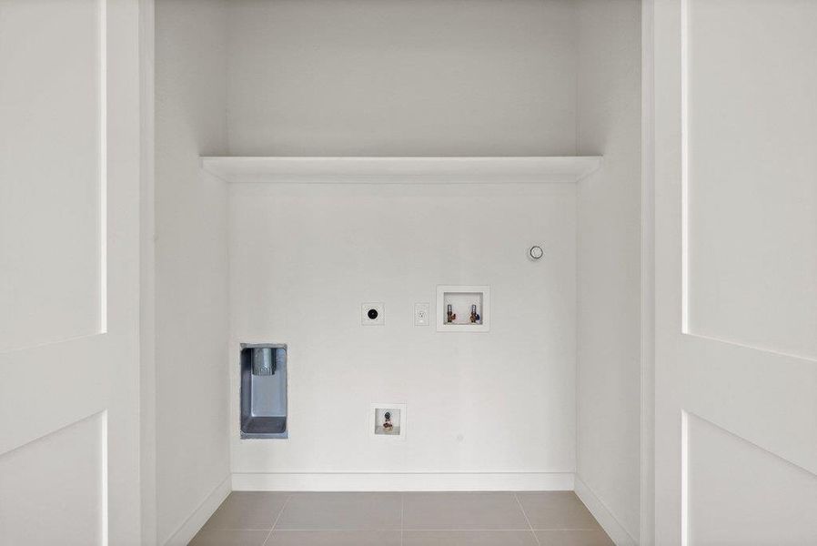 Dedicated laundry area with tiled flooring and a shelf for storage