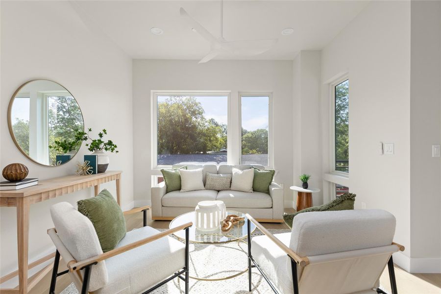 Sunlight streams through large windows onto beautiful hardwood floors in this welcoming living space.