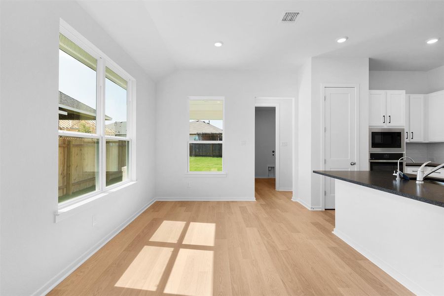 Kitchen with dark countertops, white cabinetry, recessed lighting, light wood-style flooring, and stainless steel oven Kitchen with dark countertops, white cabinetry, recessed lighting, light wood-style flooring, and stainless steel oven