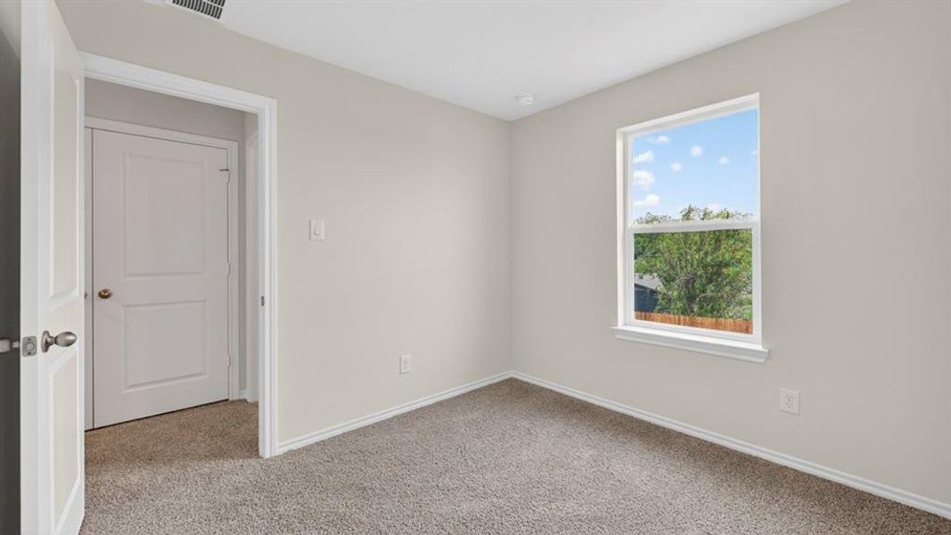 Bright room featuring neutral-toned walls, plush carpet flooring, a single window, white trim throughout, and a paneled door