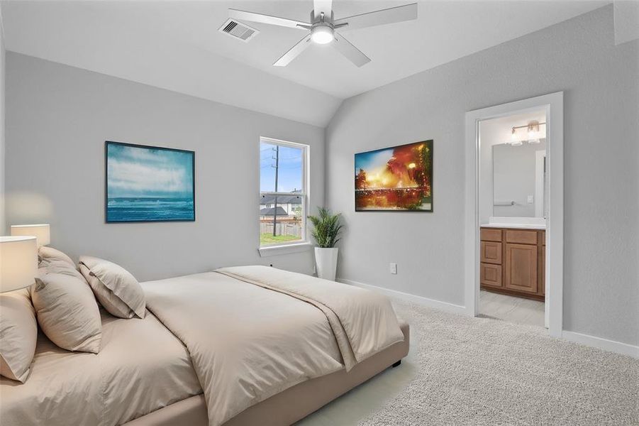 Secondary bedroom features plush carpet, custom paint, ceiling fan, large window with privacy blinds, and private access to a secondary bathroom.