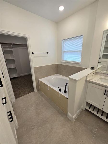 Bathroom featuring a bath, tile patterned flooring, and vanity