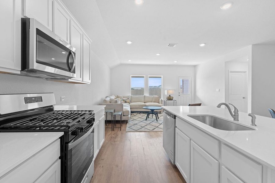 Kitchen featuring stainless steel appliances, white cabinetry, recessed lighting, light wood finished floors, and light stone counters Kitchen featuring stainless steel appliances, white cabinetry, recessed lighting, light wood finished floors, and light stone counters