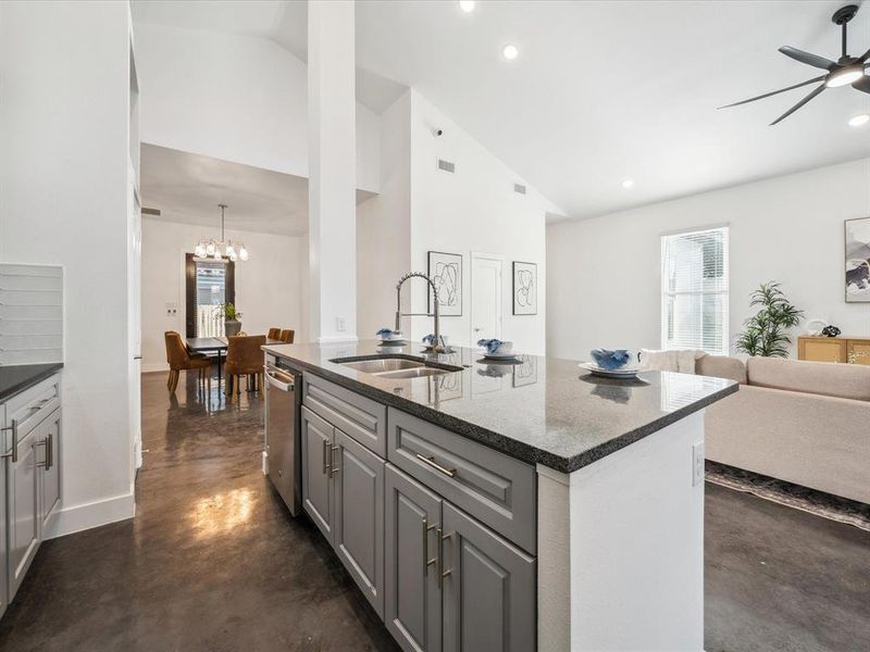 Kitchen with sink, gray cabinetry, lofted ceiling, and an island with sink