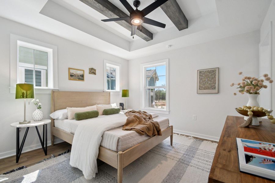 Naturally illuminated, this primary bedroom features a tray ceiling with exposed beams as an option and a modern ceiling fan. Naturally illuminated, this primary bedroom features a tray ceiling with exposed beams as an option and a modern ceiling fan.