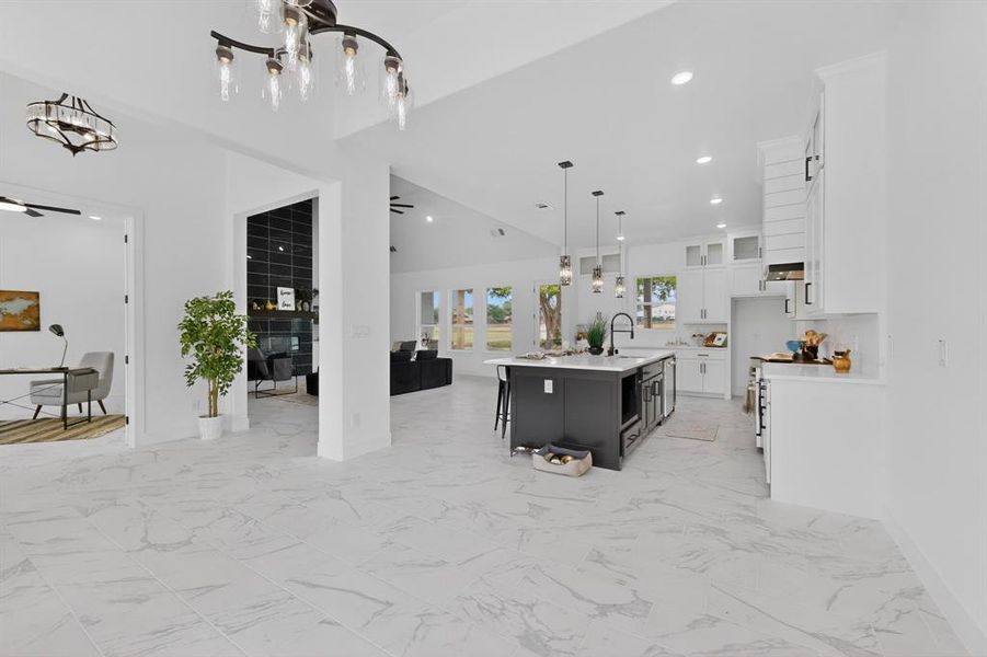Spacious open-concept interior featuring light-toned tile flooring, vaulted ceilings, and recessed lighting