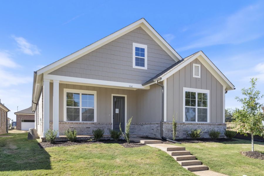 Exterior featuring a combination of vertical siding and shingle-style siding, stone veneer base, covered front porch with square columns, and grid-pattern windows Exterior featuring a combination of vertical siding and shingle-style siding, stone veneer base, covered front porch with square columns, and grid-pattern windows