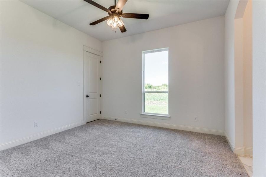 Carpeted spare room featuring ceiling fan