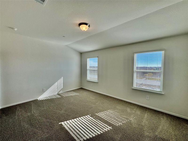 Carpeted empty room with lofted ceiling and a textured ceiling