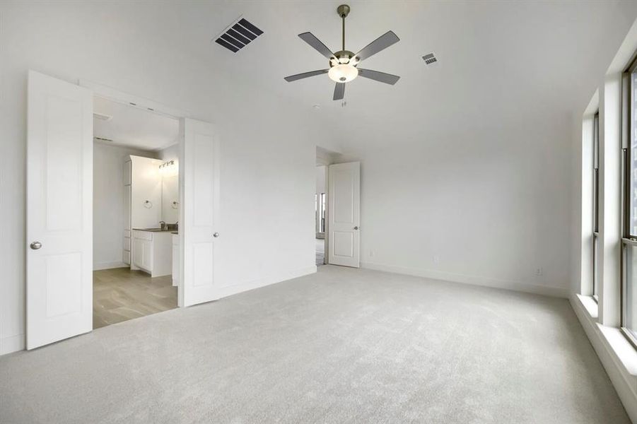 Spacious room featuring light-colored carpeting, multiple large windows, and a ceiling fan with integrated lighting Spacious room featuring light-colored carpeting, multiple large windows, and a ceiling fan with integrated lighting