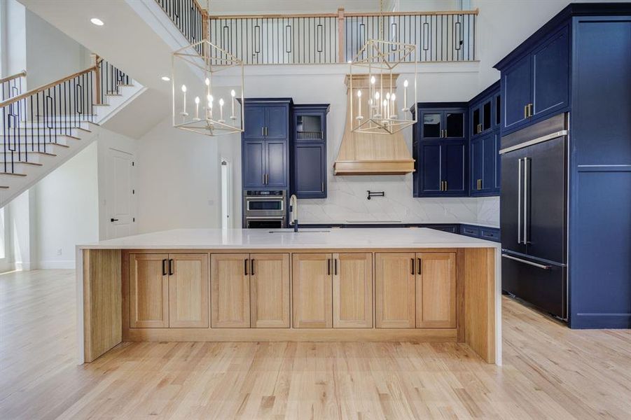 Open-concept kitchen featuring a large central island with light wood cabinetry and a white countertop
