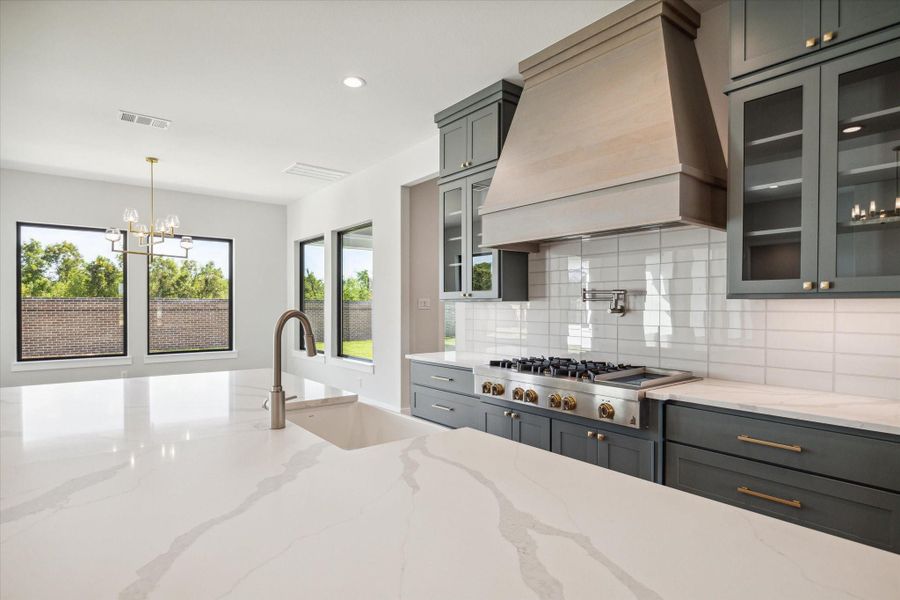 Beautiful countertops, custom-built cabinetry, and gas range complete with wall mounted pot filler faucet. Beautiful countertops, custom-built cabinetry, and gas range complete with wall mounted pot filler faucet.