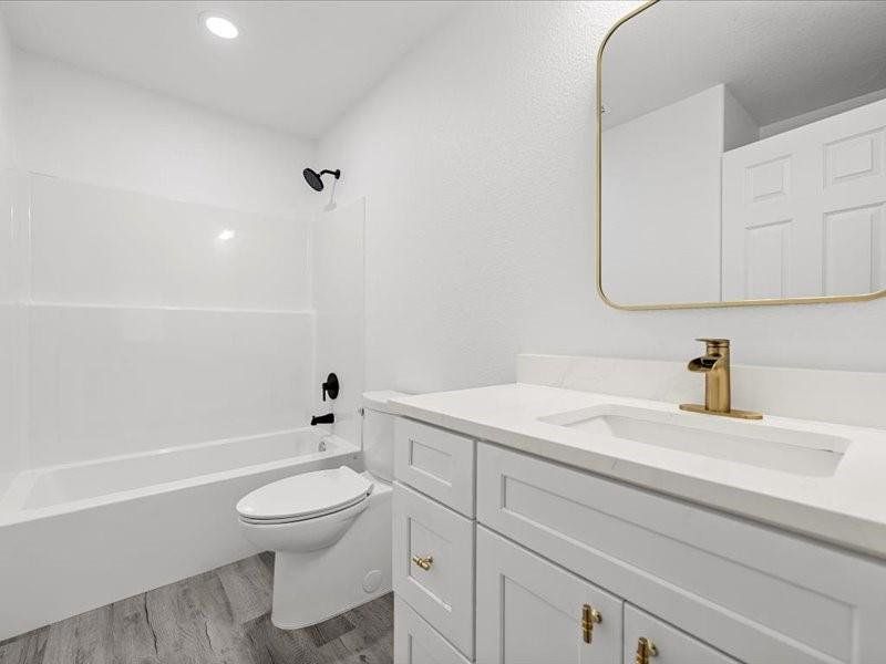 Full bathroom with washtub / shower combination, vanity, dark wood-style floors, and recessed lighting