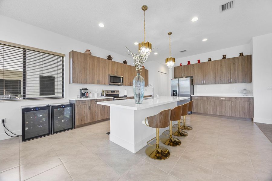 Kitchen with a breakfast bar, light tile patterned floors, beverage cooler, pendant lighting, and recessed lighting