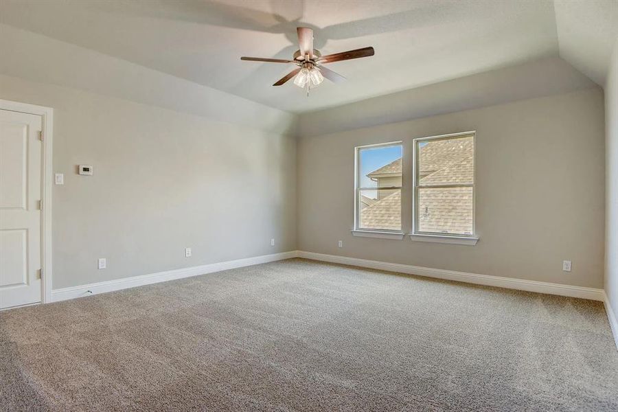 Spare room featuring carpet, vaulted ceiling, ceiling fan, and baseboards