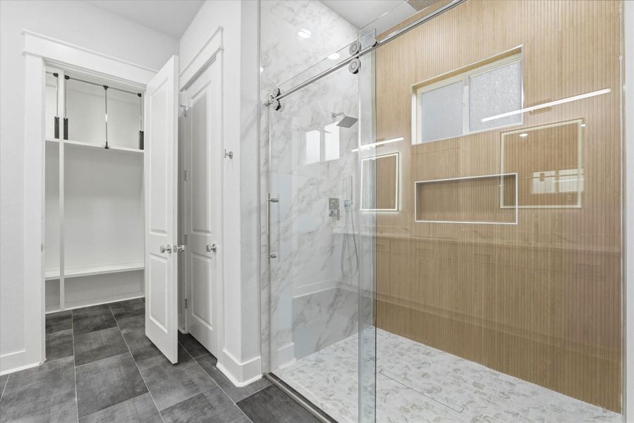 The primary bathroom also includes a spacious walk-in shower featuring a large built in soap niche, frosted glass window, and multiple shower heads. The shower is finished with sleek frameless sliding glass doors.