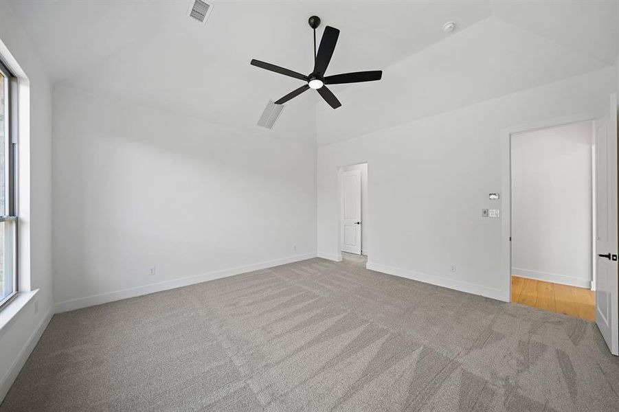 Empty room featuring light colored carpet and a ceiling fan