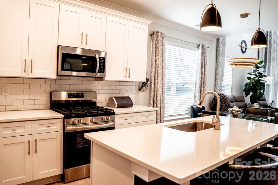 Your dream kitchen with a gas stove, updated backsplash and an oversize quartz island.