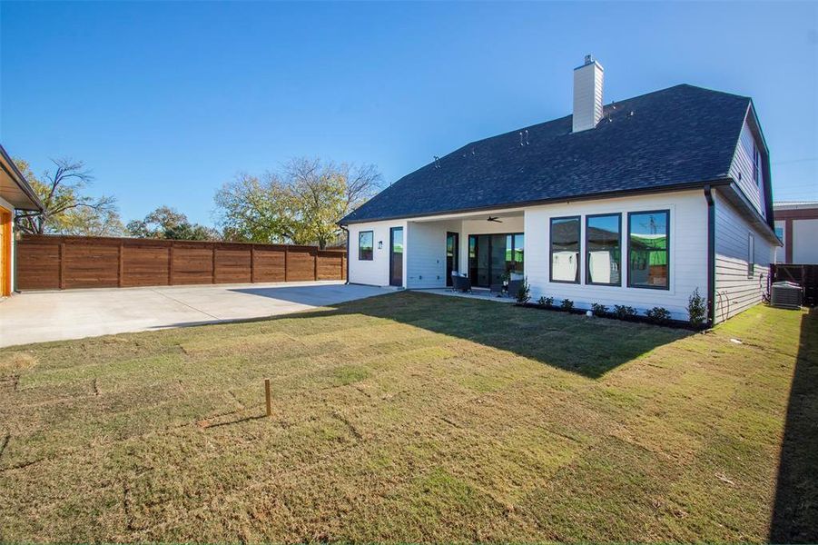 Back of property with ceiling fan, cooling unit, a patio area, and a yard