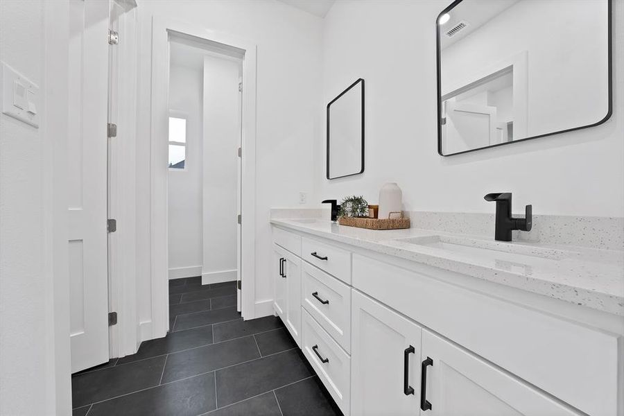 Dual vanity with white cabinetry, integrated sinks, and black hardware