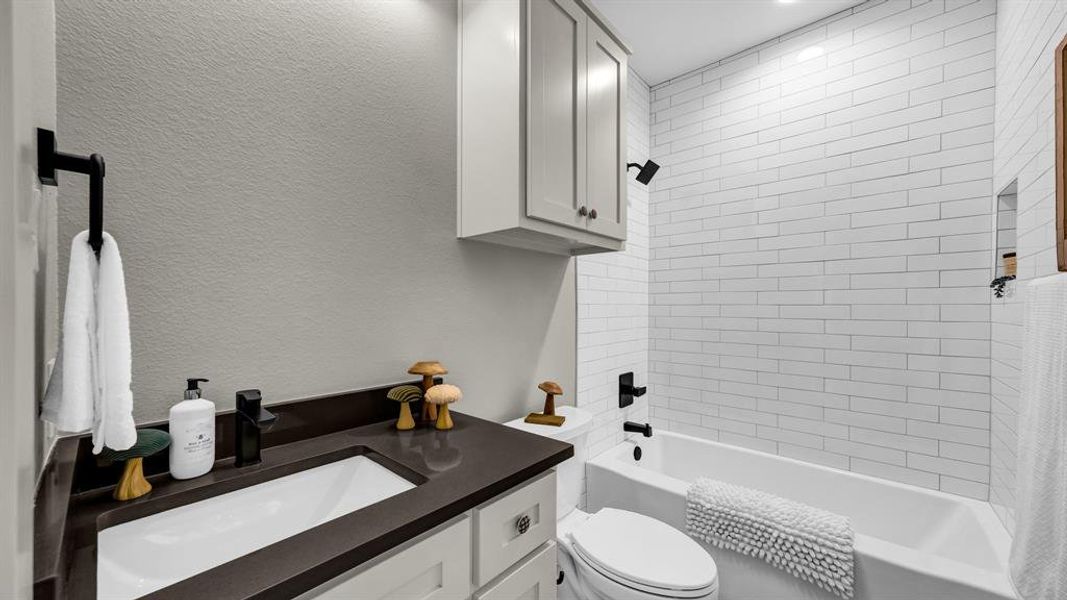 Bathroom featuring shower / tub combo, vanity, and a textured wall