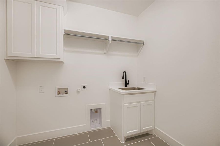 Laundry area with dark tile patterned flooring, gas dryer hookup, cabinet space, hookup for a washing machine, and hookup for an electric dryer Laundry area with dark tile patterned flooring, gas dryer hookup, cabinet space, hookup for a washing machine, and hookup for an electric dryer