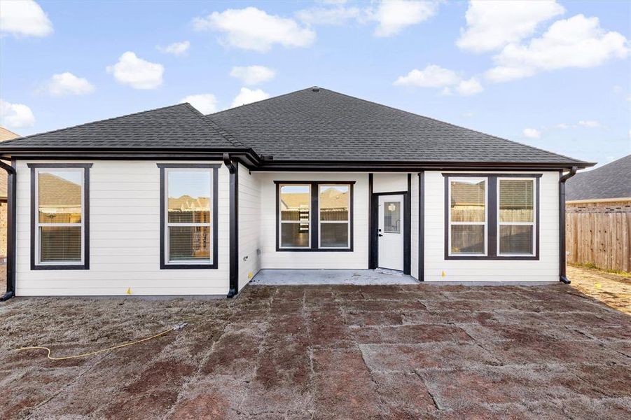 Rear view of property with a shingled roof, a patio area, and fence Rear view of property with a shingled roof, a patio area, and fence