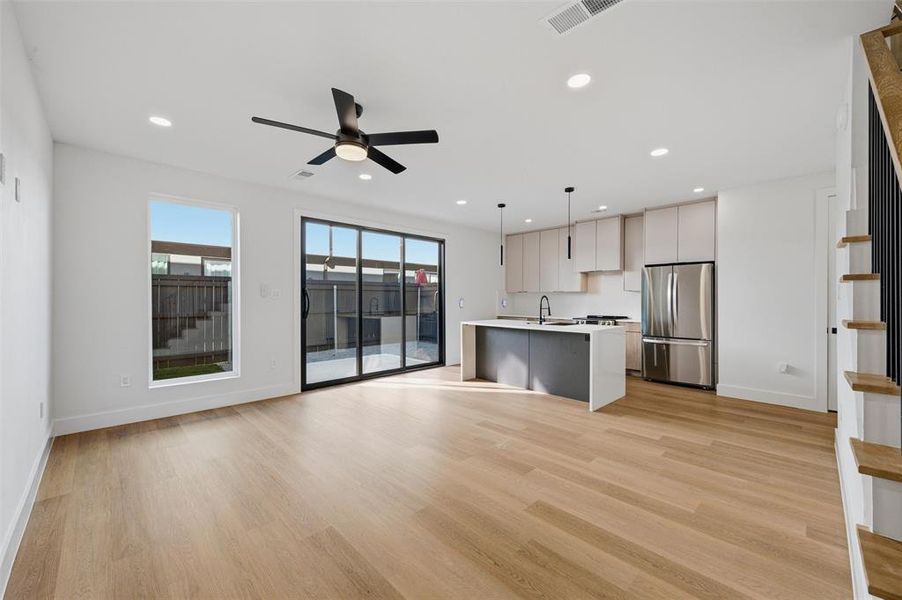 Living Room features recessed lighting and ceiling fan with light fixture. Sliding glass door provides access to the backyard patio. Open layout connects directly to the kitchen featuring pendant lighting,
gas range, and stainless steel appliances. Vinyl flooring extends throughout.