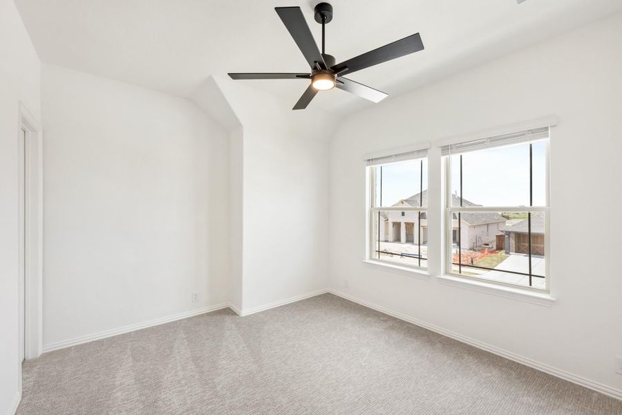 Empty bedroom with vaulted ceiling, black ceiling fan, carpet flooring, and double windows