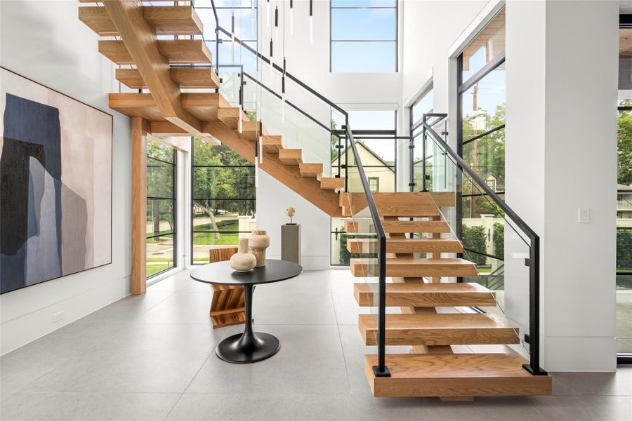 Steel and glass staircase with wood open-riser steps. Frameless glass balustrade with custom-fabricated blackened steel handrails. Steel and glass staircase with wood open-riser steps. Frameless glass balustrade with custom-fabricated blackened steel handrails.