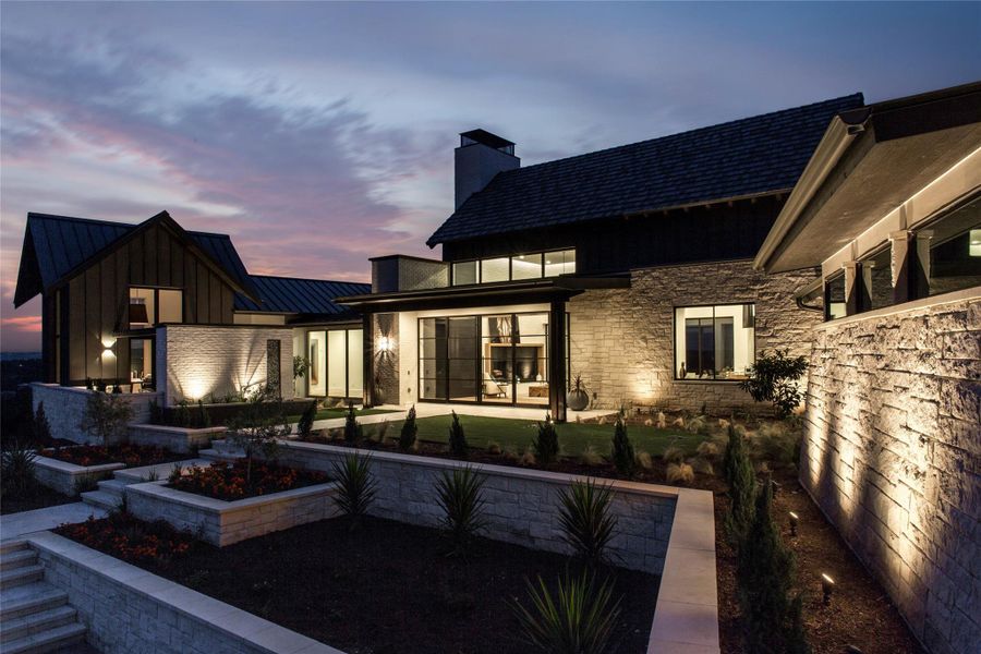Back of property at dusk featuring a standing seam roof, a metal roof, board and batten siding, and a patio