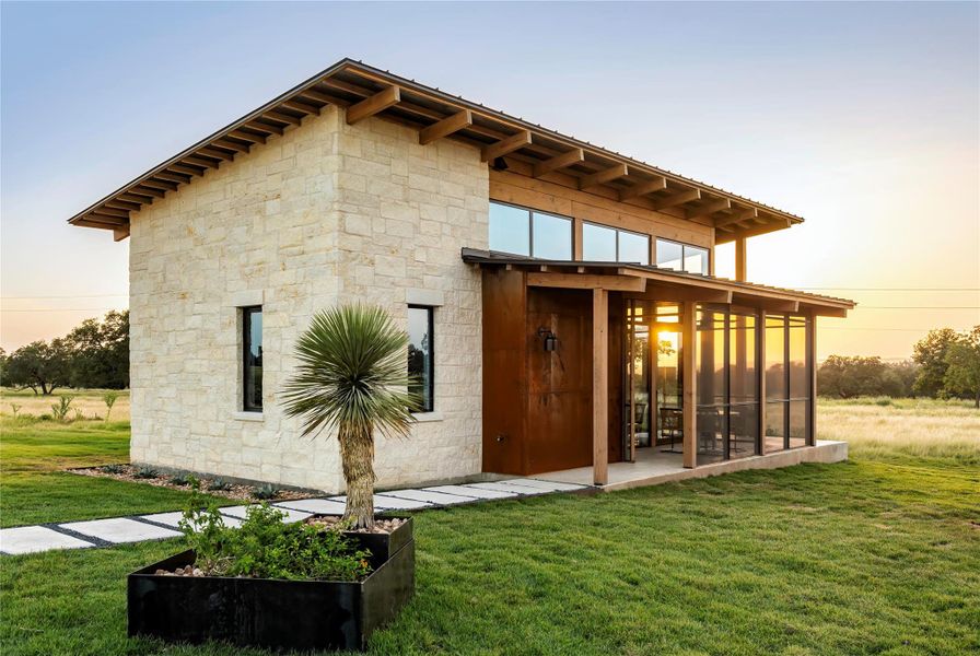 Striking modern Hill Country exterior with limestone masonry, expansive glass, and warm wood accents set against sweeping sunset views. Striking modern Hill Country exterior with limestone masonry, expansive glass, and warm wood accents set against sweeping sunset views.