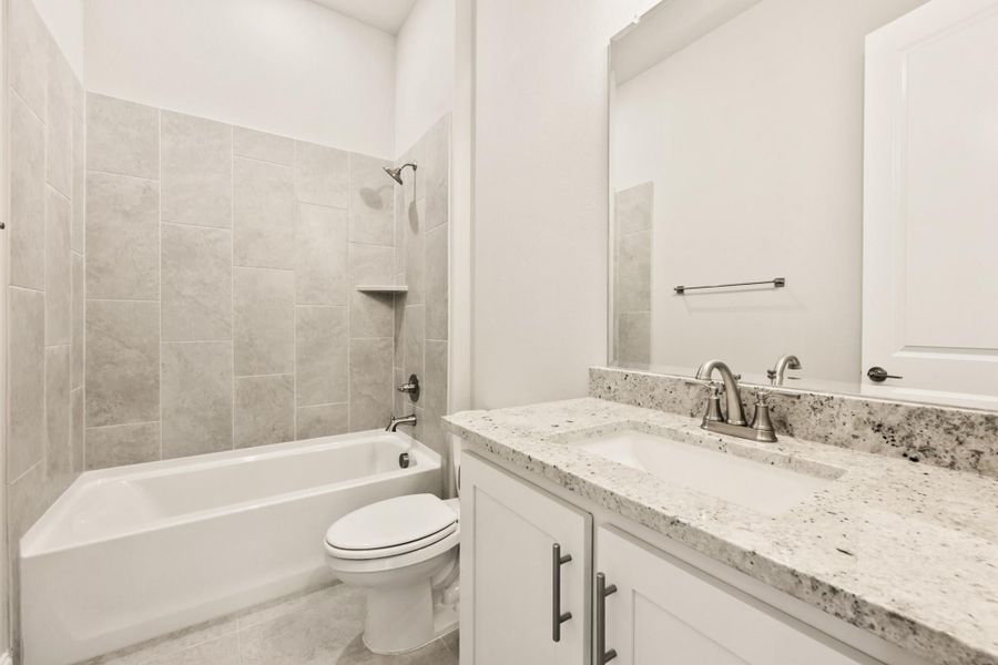 Bathroom with white vanity, granite countertop, tiled tub-shower combo, and toilet Bathroom with white vanity, granite countertop, tiled tub-shower combo, and toilet