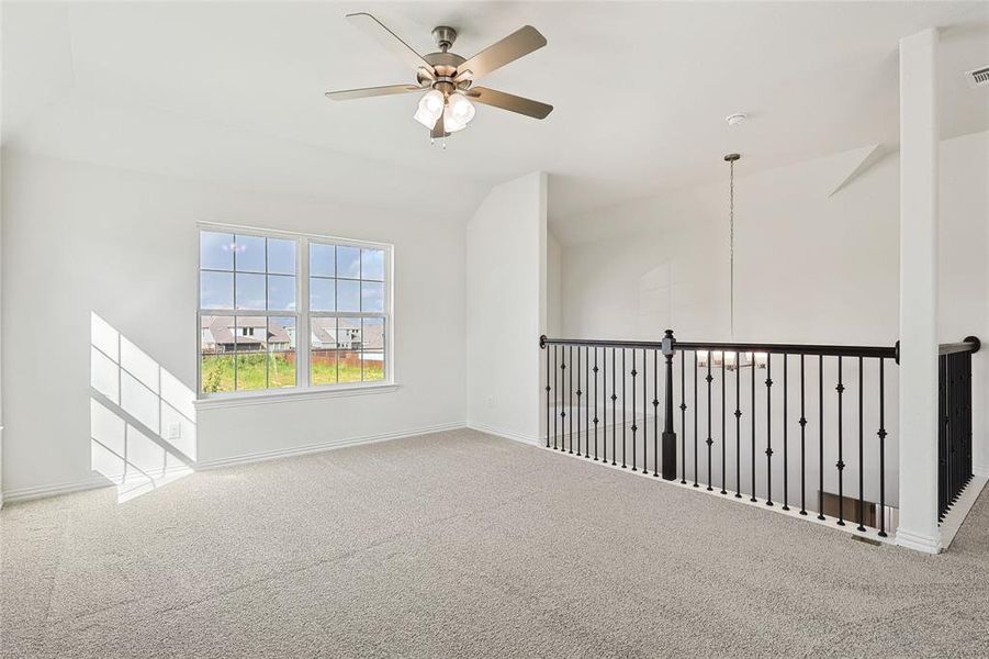 Carpeted spare room with ceiling fan and vaulted ceiling