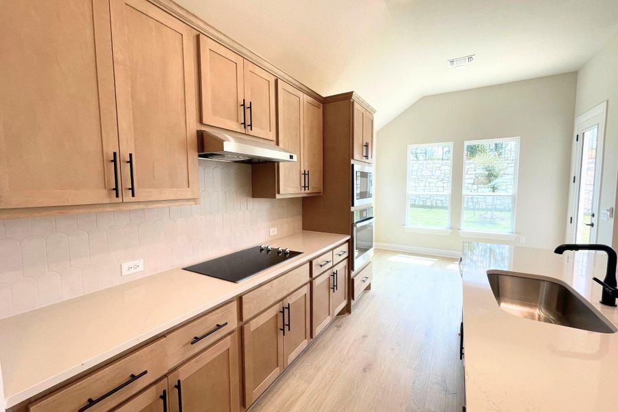 Custom cabinetry and solid stone countertops anchor a sleek, integrated culinary space. Custom cabinetry and solid stone countertops anchor a sleek, integrated culinary space.