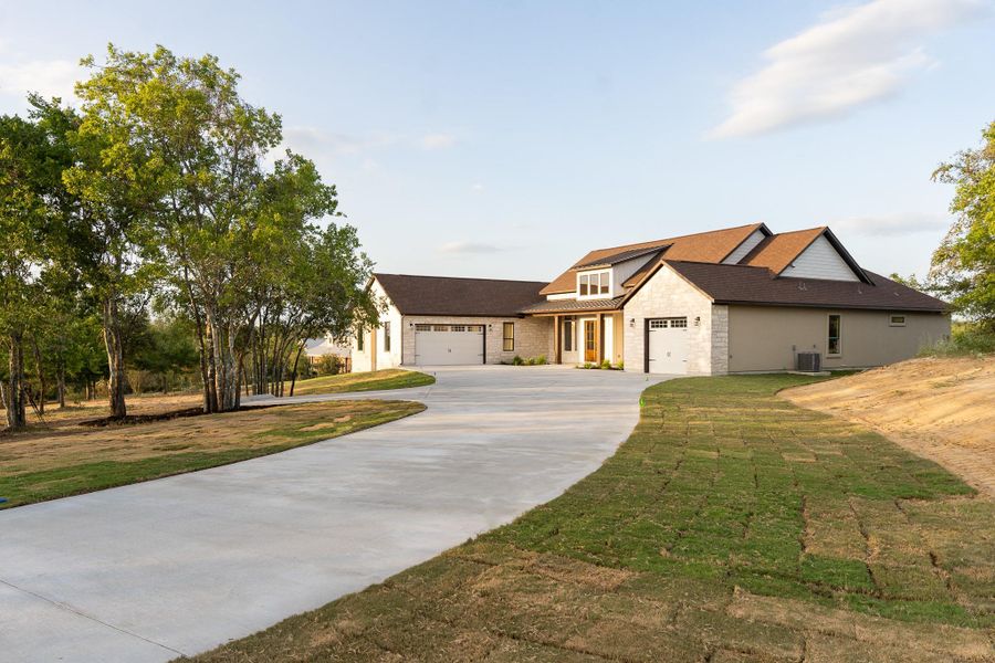 Modern farmhouse style home featuring stone siding, driveway, an attached garage, and a front lawn Modern farmhouse style home featuring stone siding, driveway, an attached garage, and a front lawn